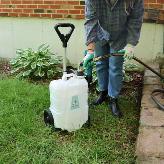 person filling up 4 gallon sprayer with a garden hose