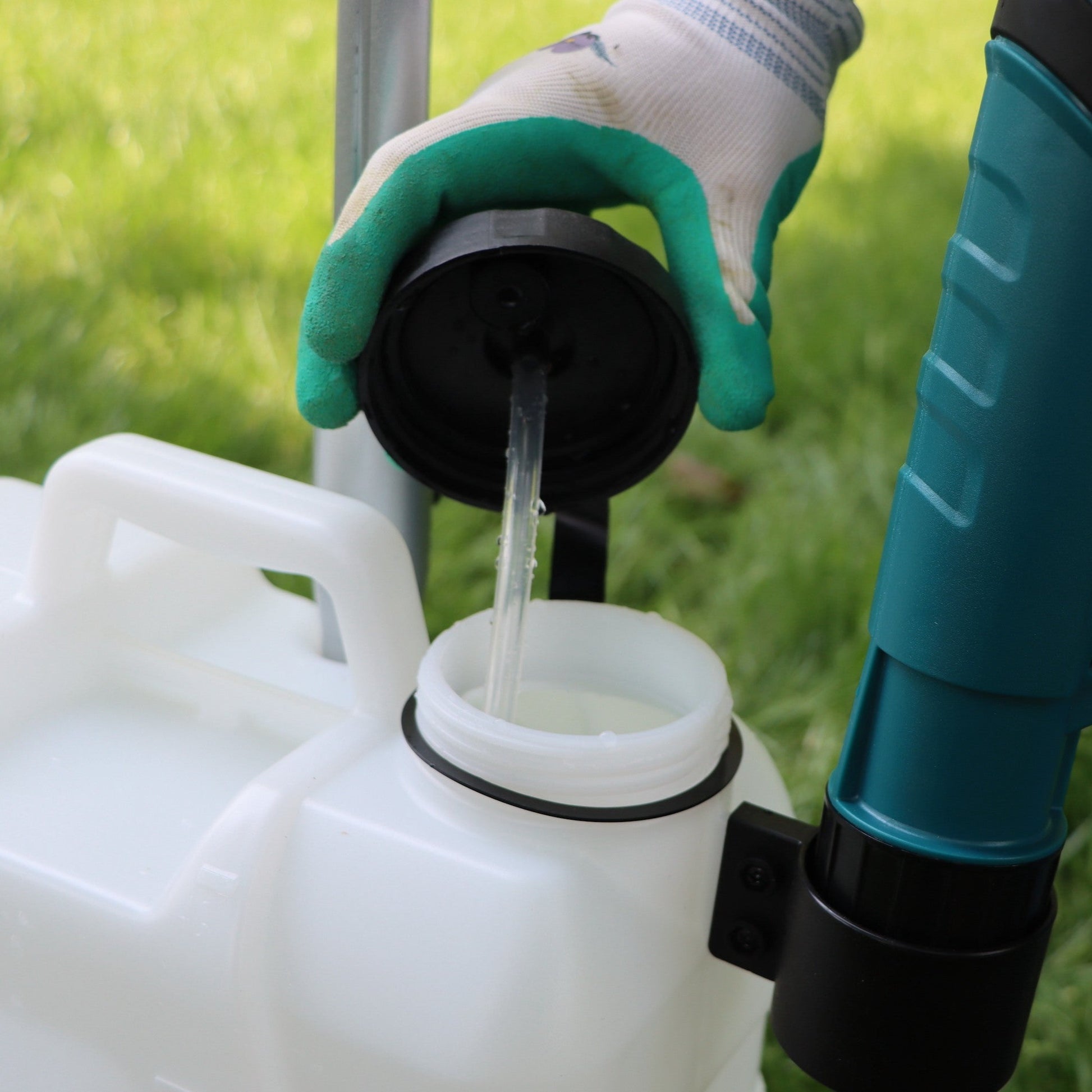 gloved hand holding open tank lid of a battery sprayer